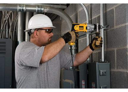 DEWALT DWD520 en uso sobre tuberías metálicas en pared de ladrillo