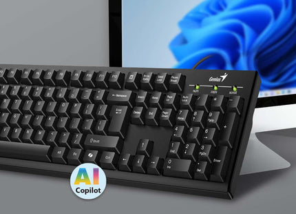 Ángulo diagonal del teclado Genius KB-100 negro sobre superficie blanca